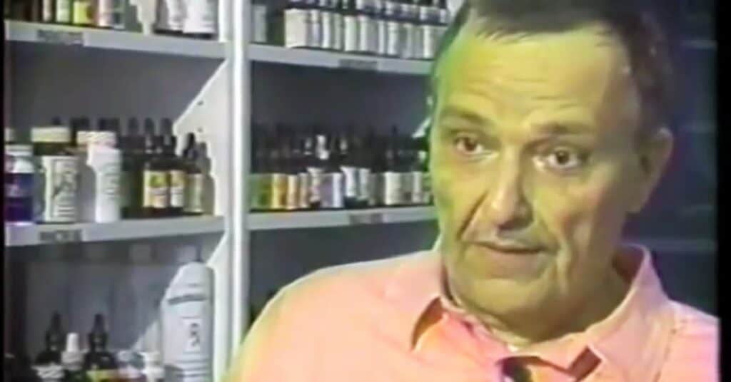 Roger Liephart in pink shirt speaking to camera, with shelves of medicine bottles and containers visible in background